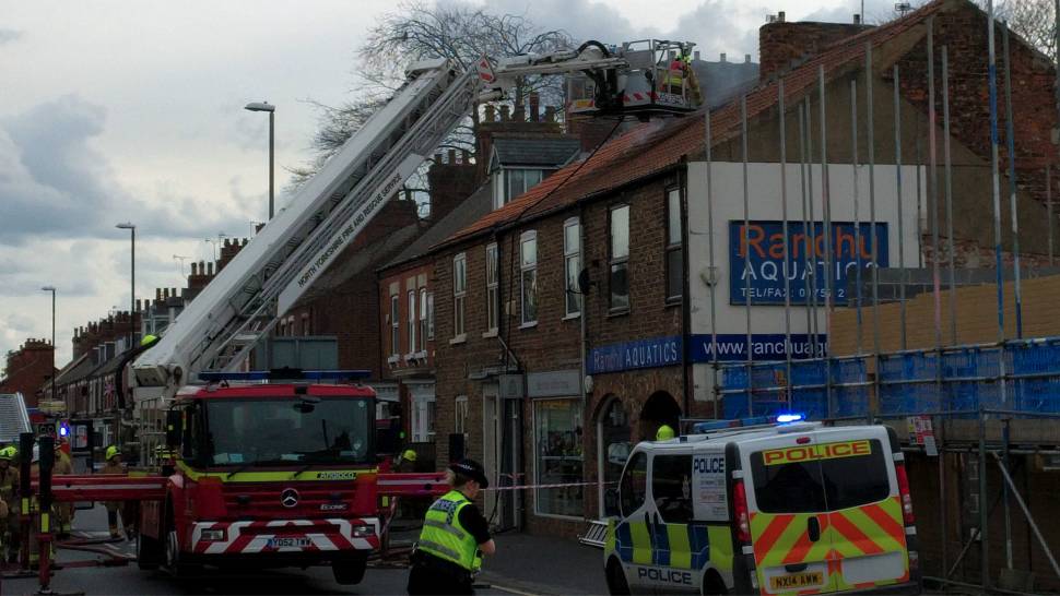 Firefighters punch hole into roof above Little Coffee House.